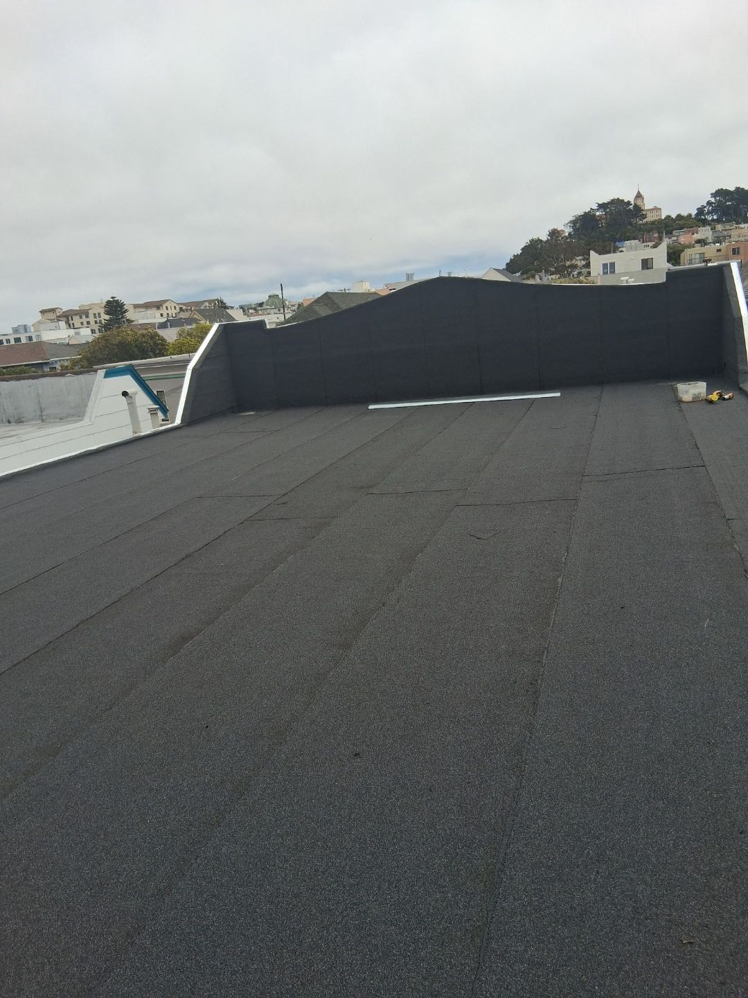 Completed gray roll roofing on a low-slope roof