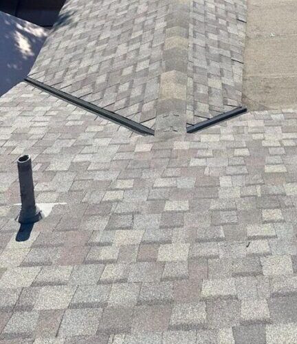 Grey architectural shingle roof with a metal valley and a vent pipe